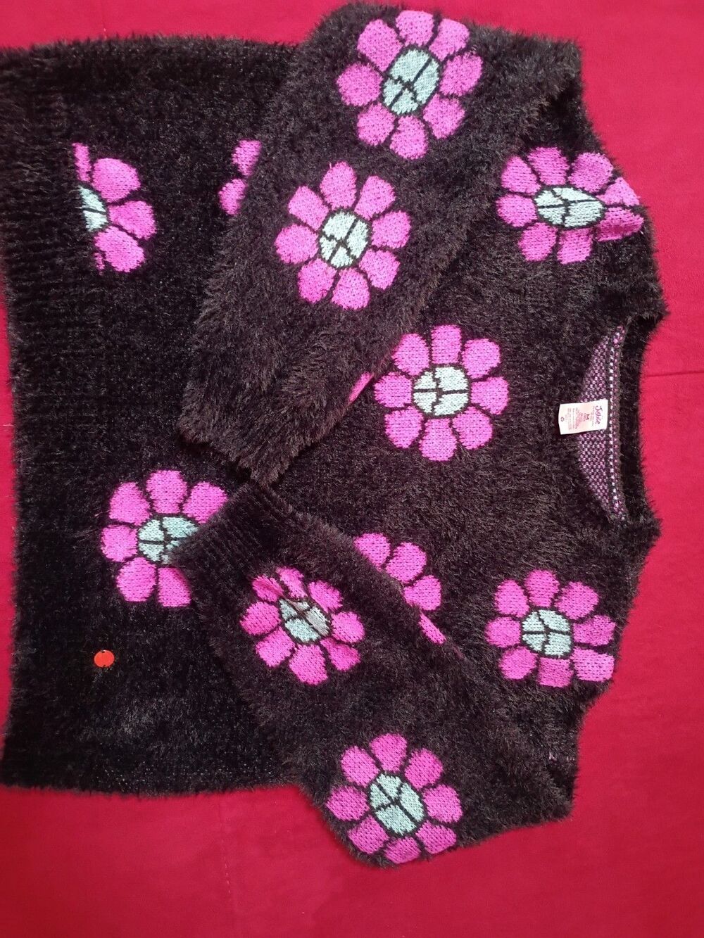 This is a Justice girls' black fuzzy eyelash sweater featuring pink and blue...